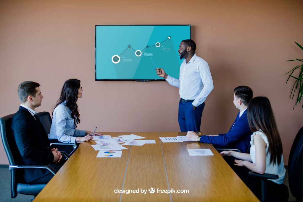 Homem faz apresentação comercial em reunião com 4 pessoas (Imagem: Freepik)