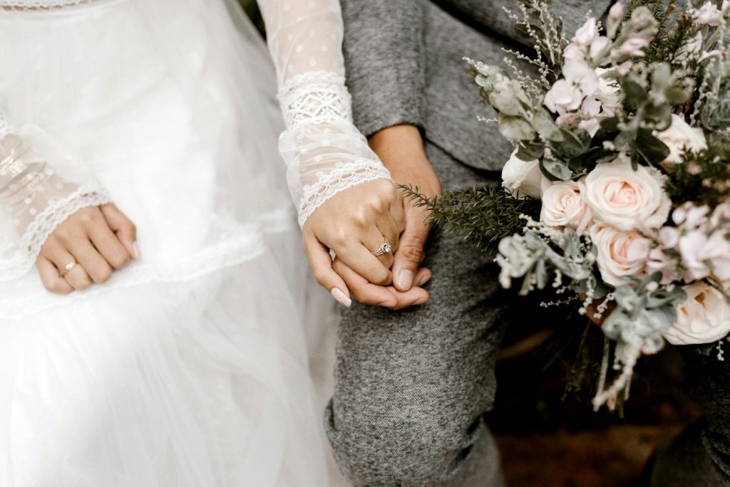 Noivos de mãos dadas ouvem emocionados o roteiro para celebrante de casamento (Imagens: Pexels)