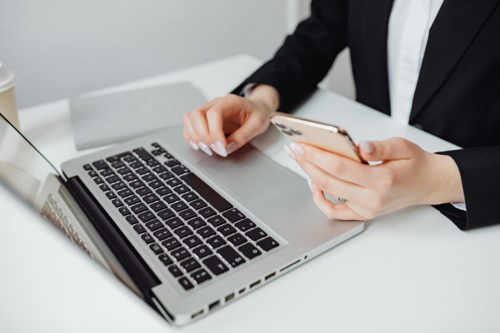 Imagem de uma mulher digitando no notebook e segurando um celular para ilustrar texto sobre blog corporativo estratégico. Foto: Pexels.
