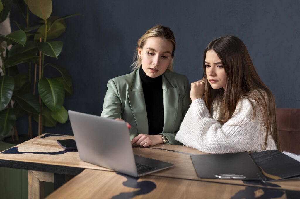 Imagem de duas mulheres, lado a lado, em frente a um notebook. Foto: Freepik