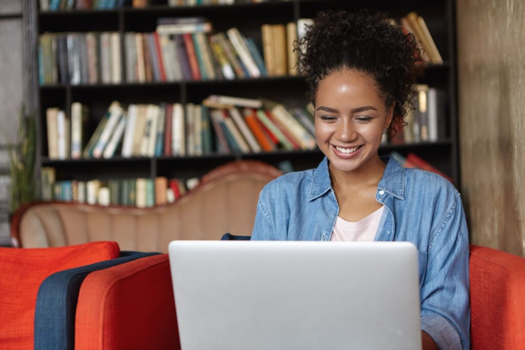 Imagem de mulher sorrindo em frente ao notebook para ilustrar artigo sobre conteúdo otimizado para SEO. Foto: Freepik